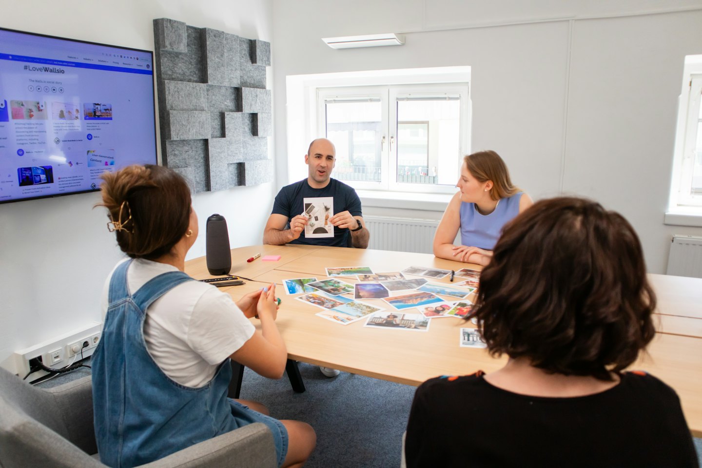 Man shows printout to women at office meeting table.