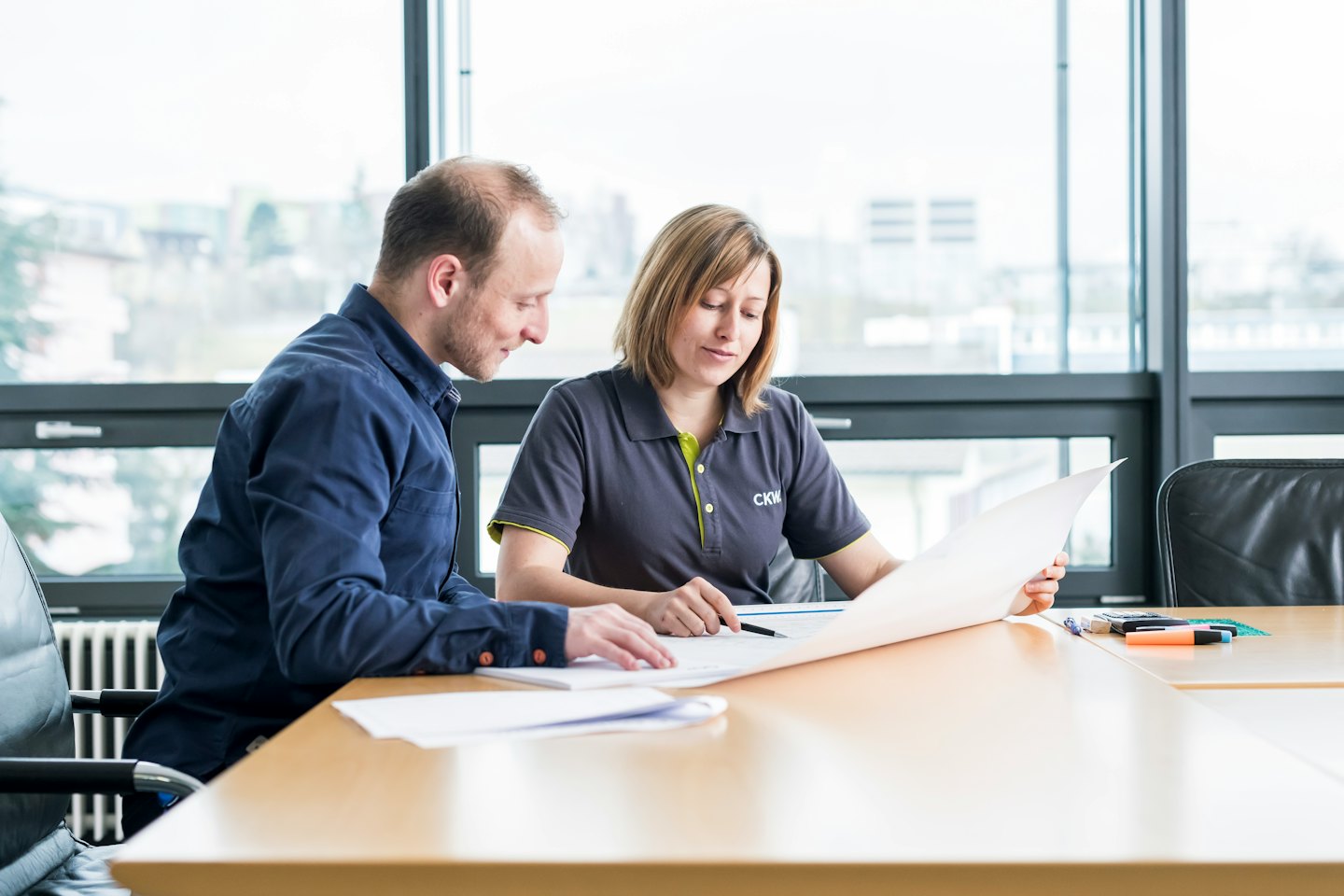 Two professionals discussing blueprints at a conference table.